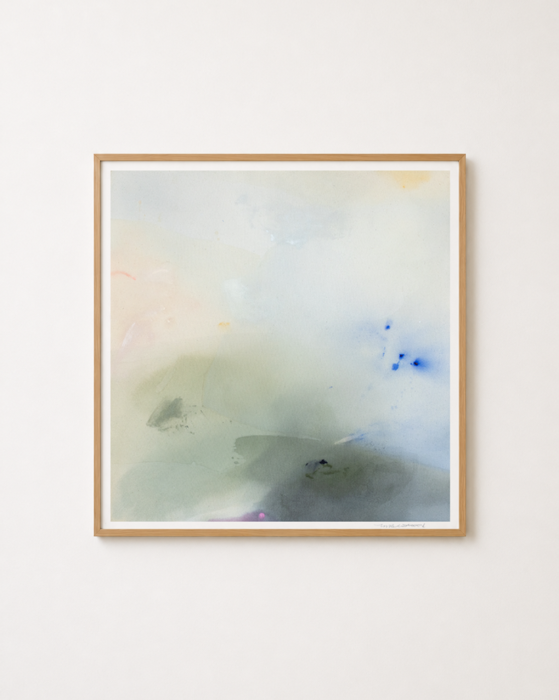 A framed abstract painting with soft blended washes of pale blue, gray, green, and faint peach tones, hung on a plain light wall.